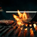 Burger cooking over flames on an outdoor barbecue grill